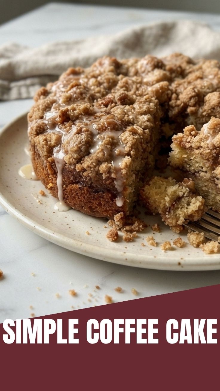 A freshly baked coffee cake with a crumble topping, served on a white plate.