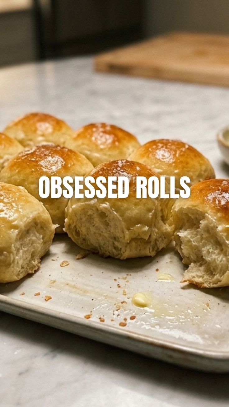 A basket of freshly baked golden brown dinner rolls.
